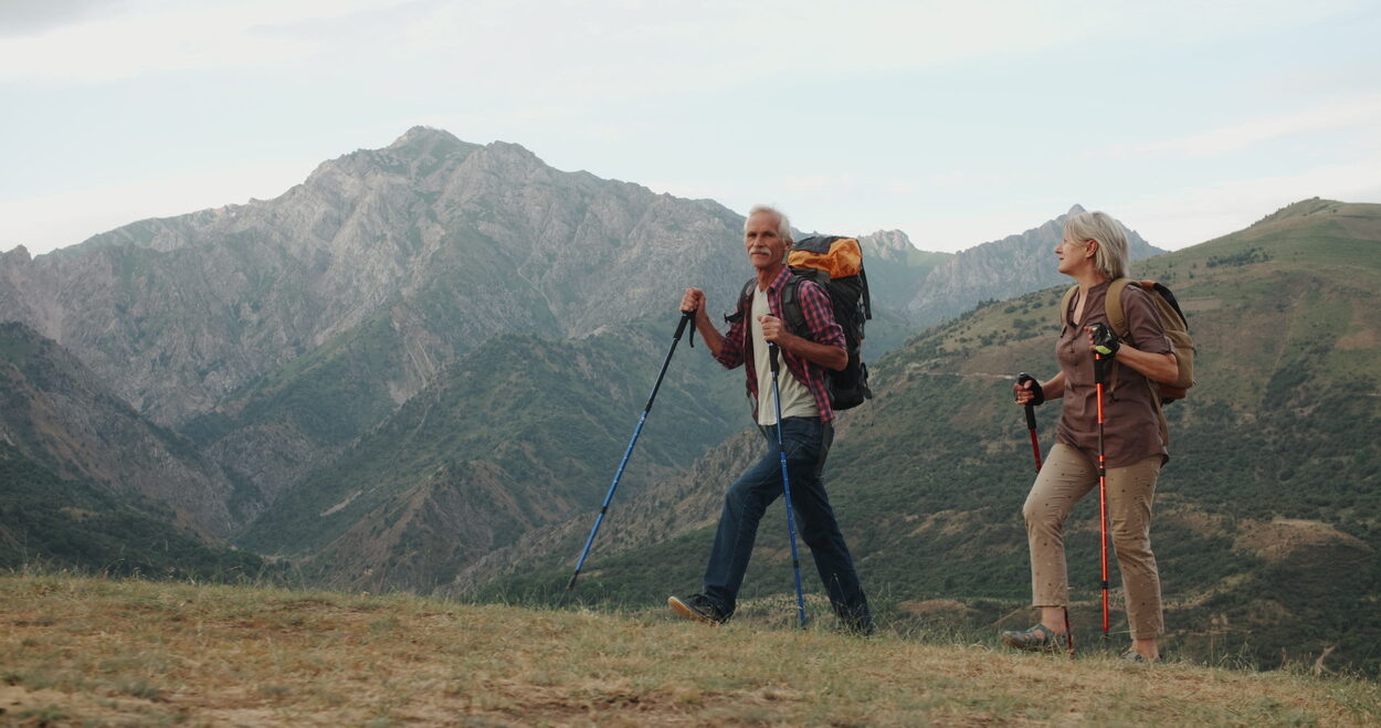 Active senior caucasian couple hiking in mountains with backpacks enjoying their adventure 4k