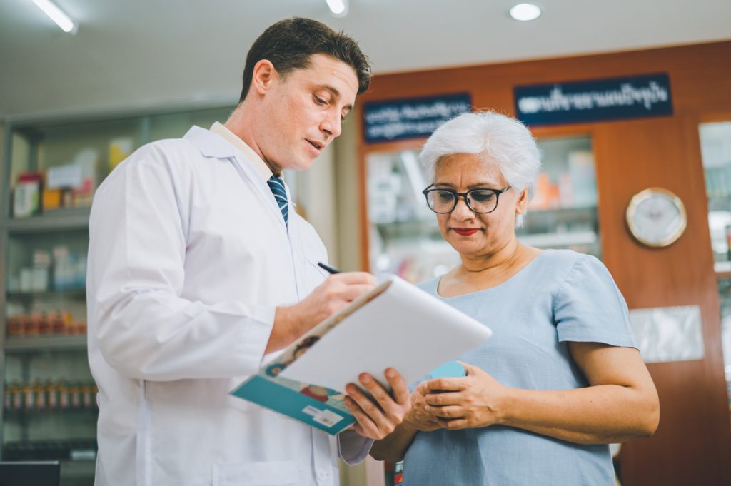 Senior woman reviewing Medicare GLP 1 prescription options with pharmacist at pharmacy
